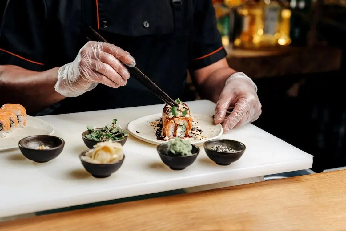 Chef plating a beautifully decorated sushi roll with fresh ingredients like microgreens at Hokkaido Sushi & Ramen, a Japanese restaurant in Vancouver at Hokkaido Sushi & Ramen, a Japanese restaurant in Vancouver